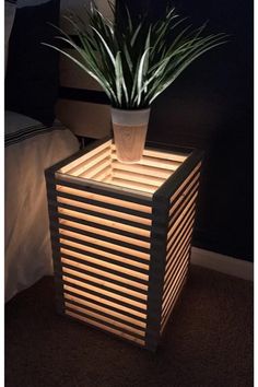 a potted plant sitting on top of a wooden box next to a night stand