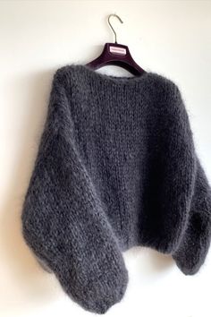 a gray sweater hanging on a white wall