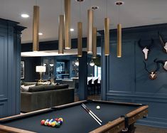 a pool table in a living room with several deer heads on the wall behind it