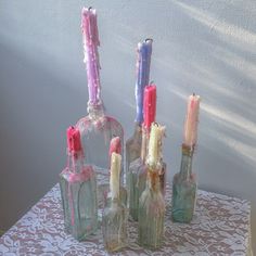 four bottles with candles in them sitting on a table