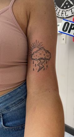 a woman's arm with a tattoo on it that has a cloud and lightning coming out of it