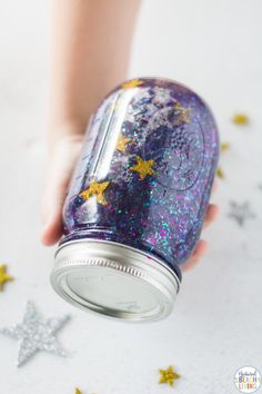 a person holding a purple jar with gold stars on it