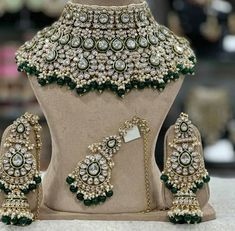 a green and white necklace set with matching earrings on display in a jewelry store window