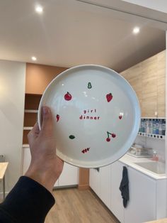 a person holding up a plate with the words girl dinner on it in front of a kitchen