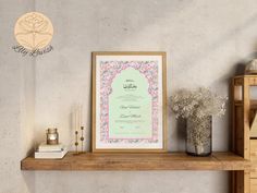 a table topped with a vase filled with flowers next to a framed paper on top of a wooden shelf