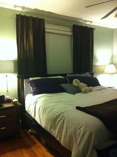 a bed with two teddy bears sitting on it's headboard in a bedroom