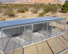 a large caged in area with several cages on the ground and mountains in the background