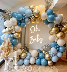 a blue and gold balloon arch with the words oh baby written in white on it