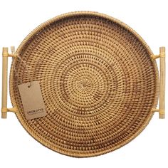 a round wicker tray with two handles and a tag on the front, sitting on a white background