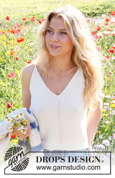 a beautiful blonde woman standing in a field full of wildflowers holding a glove