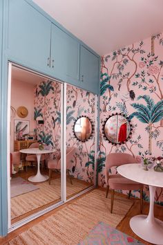 a dining room with pink chairs and wallpaper