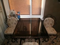 a glass table with two chairs and a cat sitting on the chair next to it