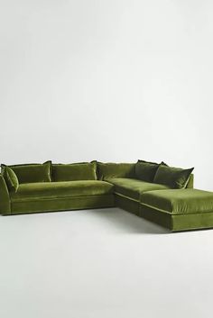 a green sectional sofa with pillows on it