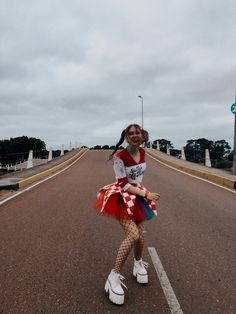 a girl in a red and white dress is standing on the street