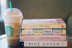 a stack of books sitting next to a starbucks drink