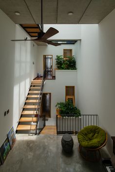 a living room filled with furniture and lots of plants on top of the stairs in front of a staircase