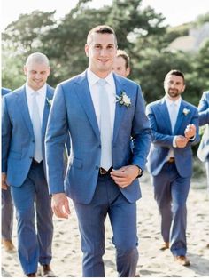 a group of men in suits walking down a beach