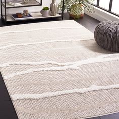 a white rug on the floor in a living room with plants and potted plants