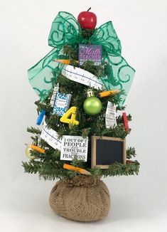 a small christmas tree decorated with school supplies and decorations, on a burlock