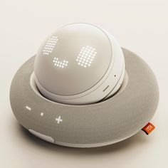 an alarm clock sitting on top of a gray object with white dots around it's eyes