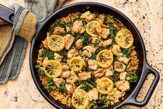 a skillet filled with chicken, rice and lemons