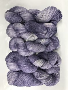 several skeins of yarn in shades of purple and white on a white surface