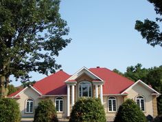 a large house with red roof and white trim on the windows, surrounded by trees