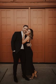 a man and woman standing next to each other in front of a brown garage door