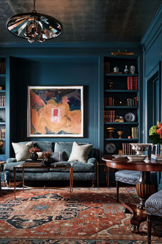 a living room filled with furniture and bookshelves next to a painting on the wall