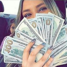 a woman is holding money in her car