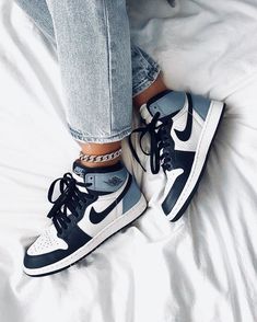 a pair of blue and white sneakers sitting on top of a bed