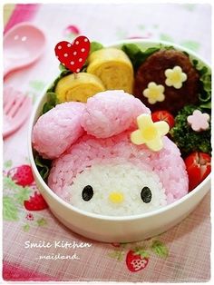 a bowl filled with lots of food sitting on top of a pink table cloth next to utensils