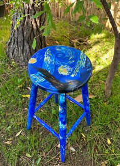 a blue stool sitting in the grass next to a tree