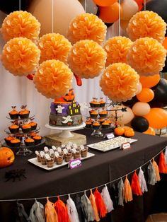 a table topped with lots of desserts and balloons in the shape of pumpkins