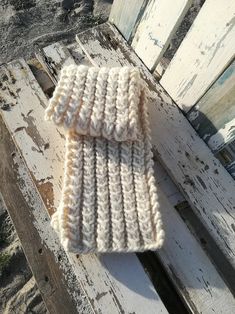 two white knitted items sitting on top of a wooden bench