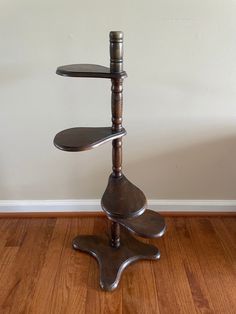 a three tiered metal stand on top of a hard wood floor next to a white wall