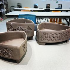 three clay bowls sitting on top of a table next to each other in front of chairs