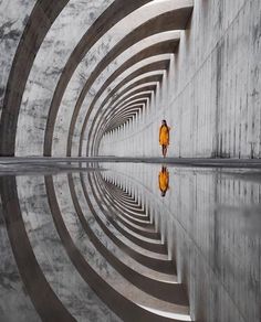 two people walking through a tunnel with their reflection in the water