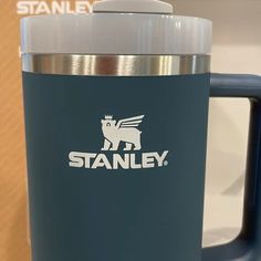 a stainless steel travel mug with the name stanley on it and a blue handle is shown