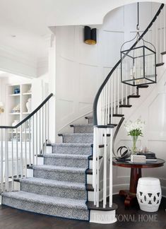 a white staircase with blue carpet and black railing