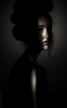 black and white photograph of a woman's head with hair in the air, dark background