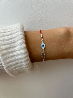 Keep yourself doubly  protected with this bracelet that combines a red string and an evil eye on a sterling silver chain. D E T A I L S *The focal point is an oval mother of pearl evil eye. *It has been  wire wrapped to a beautiful sterling silver sequin chain and a twisted nylon cord.  *A small sterling silver hammered circle charm hangs down  adding a pretty detail. *It closes with a hall marked spring ring clasp measuring 6mm. *Bracelet comes with an explanatory card and is gift ready. S I Z Handmade Silver Evil Eye Bracelet For Friendship, Red Minimalist Sterling Silver Bracelets, Handmade Dainty Silver Evil Eye Bracelet, Silver Dainty Handmade Evil Eye Bracelet, Dainty Handmade Silver Evil Eye Bracelet, Red Sterling Silver Jewelry For Friendship, Red Evil Eye Bracelet Gift, Red String Of Fate Bracelet, String Of Fate