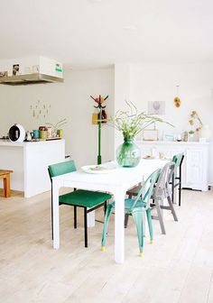 a white table with green chairs in a room