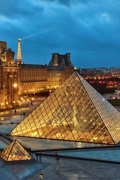 the pyramids are lit up at night in front of an old building with many windows