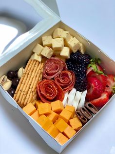 a white box filled with cheese, crackers and fruit