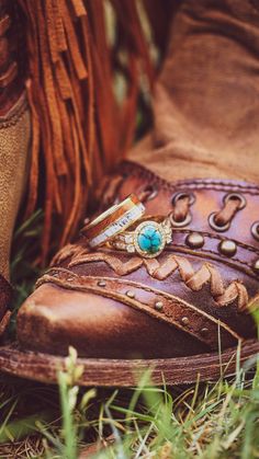 Two wedding rings sit on top of leather cowgirl boots. Below is the "Fancy" design engagement ring in 14K yellow gold with an oval cabochon turquoise center stone, diamond halo, & diamond accents. On top is the "Dyad" design wedding band in 14K yellow gold with ironwood & antler inlays. These rings are fully customizable. Find or design your dream wedding rings today with Staghead Designs! Whiskey Barrel Wedding Ring, Turquoise Engagement Ring, Antler Wedding Rings, Turquoise Wedding Rings, Antler Wedding Band, Turquoise Ring Engagement, Dream Wedding Ring, Handcrafted Engagement Ring, Wood Wedding Ring