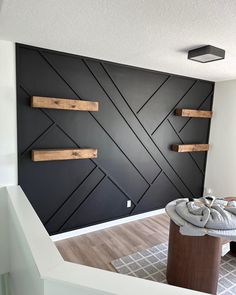 an empty room with black walls and wooden shelves on the wall, in front of a gray rug