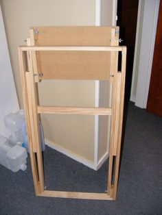 a wooden shelf sitting on top of a carpeted floor next to a white wall