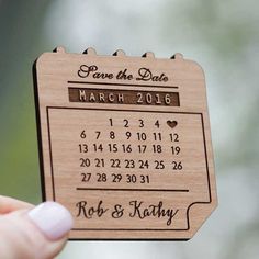 a wooden save the date magnet is held up to show it's date and location