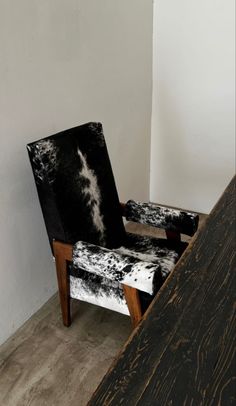 a black and white chair sitting on top of a wooden floor next to a wall